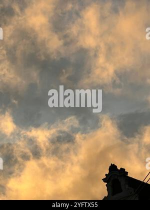 Un ciel doré au coucher du soleil rempli de nuages texturés contraste avec la silhouette sombre d'un bâtiment historique de Vienne, en Autriche Banque D'Images