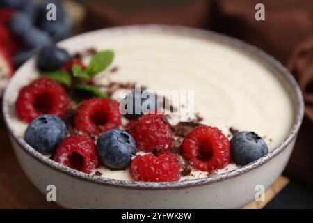 Savoureux porridge de semoule cuit avec des baies, du chocolat et de la menthe sur la table, gros plan Banque D'Images