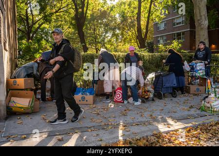 Les gens passent devant les clients devant la Manor Community Church à Chelsea à New York lors de la distribution de nourriture de leur garde-manger le samedi 26 octobre 2024. (© Richard B. Levine) Banque D'Images