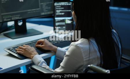 Personne paraplégique travaillant dans l'espace de travail du hub de serveur inclusif, tapant sur PC. Femme en fauteuil roulant effectuant des tâches dans le centre de données abritant l'infrastructure avancée de stockage de données, caméra A. Banque D'Images