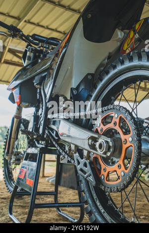 Balikpapan, Indonésie - 7 septembre 2024. La roue arrière d'un vélo de Motocross est montrée dans une pose dynamique, avec la chaîne tendue et prête à l'action. Banque D'Images