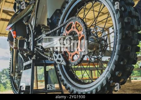 Balikpapan, Indonésie - 7 septembre 2024. Gros plan de la roue arrière d'une moto de Motocross, mettant en valeur sa puissante chaîne d'entraînement et son design robuste. Banque D'Images