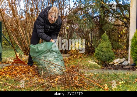 La femme nettoie dans le jardin, ratisse les feuilles, ramasse l'herbe coupée Banque D'Images