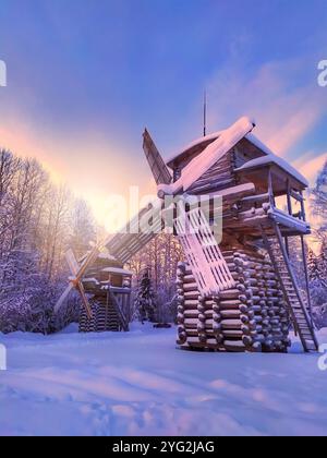 Un moulin à vent en bois se tient dans la neige. Le ciel est un beau mélange de bleu et de rose, créant une atmosphère sereine et paisible. Banque D'Images
