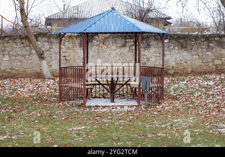 Un gazebo situé à l'extérieur avec une table et des bancs à l'intérieur, en métal avec un toit bleu. Un lieu de détente où vous pouvez vous asseoir avec compagnie, manger ou Banque D'Images