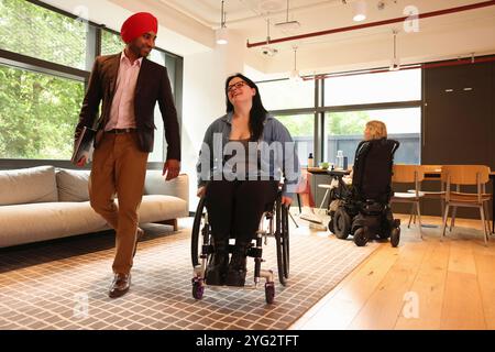 Homme d'affaires portant turban sikh et femme d'affaires sur fauteuil roulant au bureau Banque D'Images