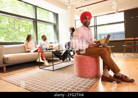 Homme d'affaires portant turban sikh assis avec ordinateur portable au bureau Banque D'Images