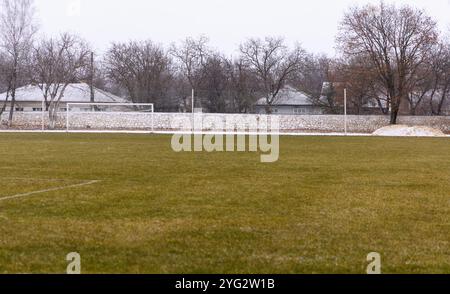 Une vue d'un terrain de football vide recouvert d'herbe avec des portes et des stands pour les spectateurs, en hiver pendant la saison froide Banque D'Images