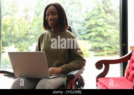 Femme en fauteuil roulant à l'aide d'un ordinateur portable Banque D'Images