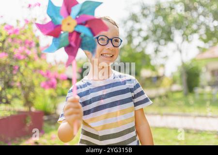 Garçon dans les lunettes joue avec la roue à épingles dans un jardin Banque D'Images