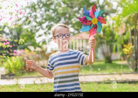 Garçon dans les lunettes joue avec la roue à épingles dans un jardin Banque D'Images