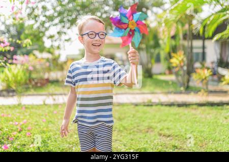 Garçon dans les lunettes joue avec la roue à épingles dans un jardin Banque D'Images