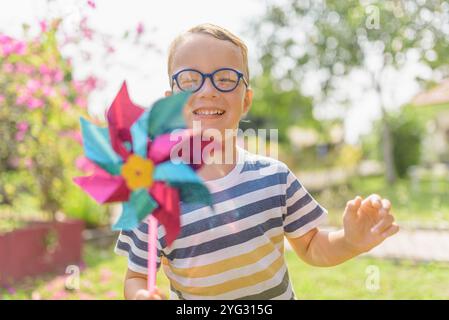 Garçon dans les lunettes joue avec la roue à épingles dans un jardin Banque D'Images