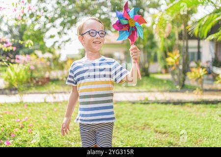 Garçon dans les lunettes joue avec la roue à épingles dans un jardin Banque D'Images