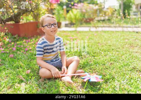 Garçon dans les lunettes joue avec la roue à épingles dans un jardin Banque D'Images