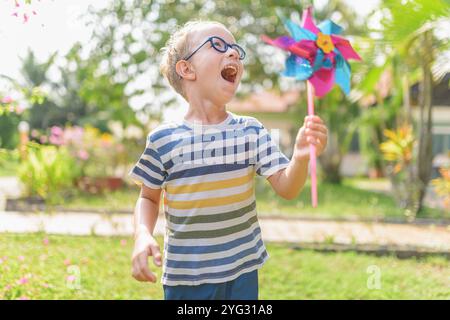 Garçon dans les lunettes joue avec la roue à épingles dans un jardin Banque D'Images