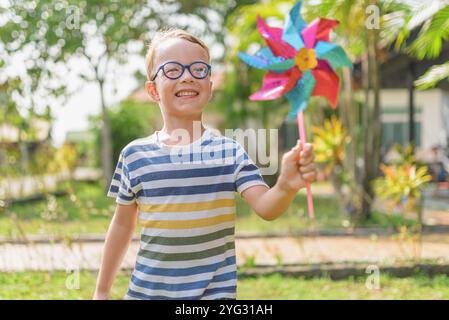 Garçon dans les lunettes joue avec la roue à épingles dans un jardin Banque D'Images