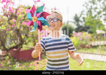 Garçon dans les lunettes joue avec la roue à épingles dans un jardin Banque D'Images