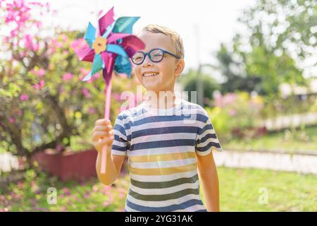 Garçon dans les lunettes joue avec la roue à épingles dans un jardin Banque D'Images