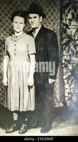 Novi Sad, Yougoslavie - années 1930 : photo vintage d'un couple marié posant devant des draperies colorées Banque D'Images