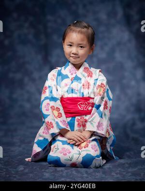 Fille de sept ans assise debout en yukata avec un visage composé Banque D'Images