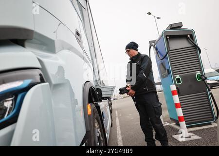 Hambourg, Allemagne. 06 novembre 2024. Rüdiger Düring, employé, se tient debout avec un câble de charge rapide sur un camion électrique 'Iveco S-eway' à côté d'une station de charge lors d'un événement de presse pour l'ouverture d'un hub de charge pour camions électriques au Cruise Center Steinwerder dans le port de Hambourg. Crédit : Christian Charisius/dpa/Alamy Live News Banque D'Images