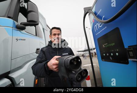 Hambourg, Allemagne. 06 novembre 2024. Mario Männlein, responsable des entraînements alternatifs chez Iveco Magirus AG, tient un câble de charge à côté d'un camion électrique 'Iveco S-eway' lors d'un événement de presse pour l'ouverture d'un hub de charge pour camions électriques au Cruise Center Steinwerder dans le port de Hambourg. Crédit : Christian Charisius/dpa/Alamy Live News Banque D'Images