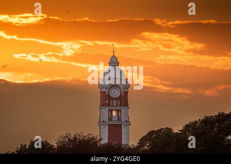 Tour de l'horloge de la ville historique de la gare ferroviaire au coucher du soleil avec le ciel dramatique et les oiseaux. Panorama paysage de Varna, Bulgarie Banque D'Images