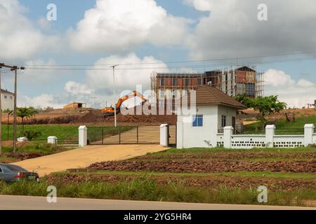 Chantier de construction urbaine avec excavatrice et échafaudage sous un ciel nuageux à Enugu, Nigeria Banque D'Images