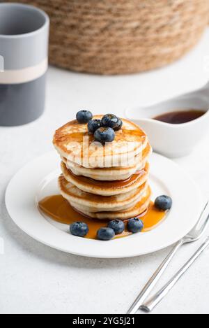 Pile de crêpes au babeurre avec myrtilles et sirop sucré sur une assiette blanche Banque D'Images