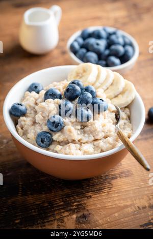 Bol de porridge d'avoine avec des bleuets et de la banane sur fond de table en bois ancien Banque D'Images