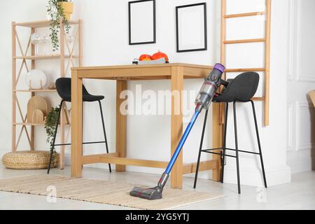 Un aspirateur sans fil reposant sur un tabouret à l'intérieur Banque D'Images
