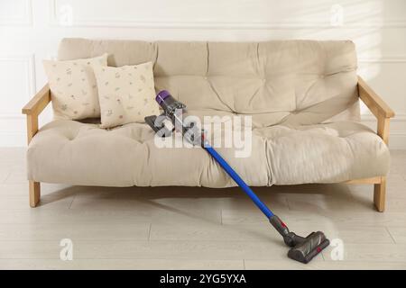 Un aspirateur sans fil reposant sur le canapé à l'intérieur Banque D'Images