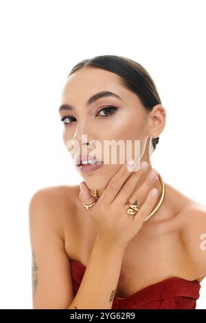 Une jeune femme gracieuse pose avec sa main sur son visage, soulignant les détails exquis de bijoux. Banque D'Images