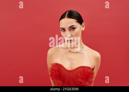 Une jeune femme magnifique met en valeur sa beauté dans un ensemble rouge vif tout en posant avec confiance. Banque D'Images