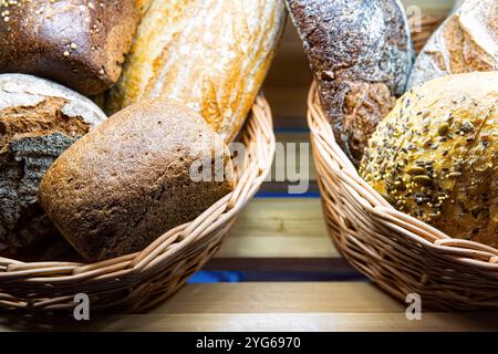 Différents types de pain frais dans le panier sur l'étagère dans la boulangerie. Banque D'Images