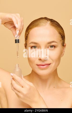 Cette jeune femme applique joyeusement des soins de la peau, soulignant sa beauté naturelle et sa confiance. Banque D'Images