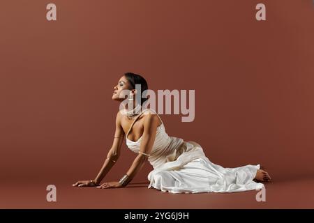 Une superbe femme afro-américaine se prélasse dans une robe blanche ornée de perles, exsudant la grâce et la beauté. Banque D'Images