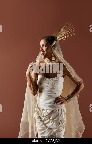 Une superbe femme afro-américaine dans une robe blanche et collier de perles captive le studio par sa présence radieuse. Banque D'Images