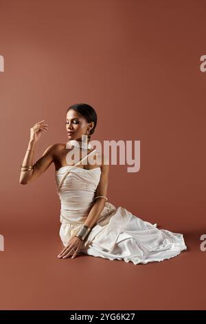 Une femme afro-américaine élégante dans une superbe robe blanche captive avec ses accessoires de perles et son calme. Banque D'Images