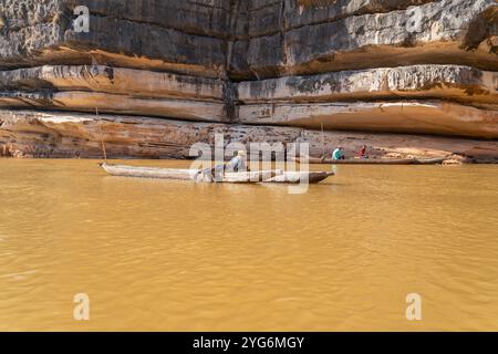 Rivière Manambolo, Madagascar - 28 août 2024 : les bateliers locaux se reposent sur des canoës d'égout pendant que les touristes explorent les formations calcaires uniques le long du YE Banque D'Images