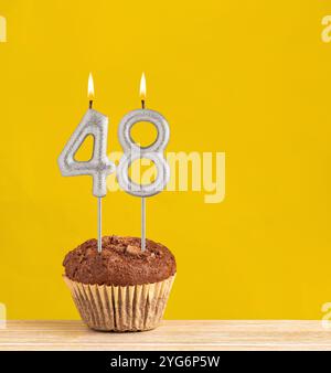 Cupcake au chocolat avec numéro 48 bougie - anniversaire sur fond jaune. Banque D'Images