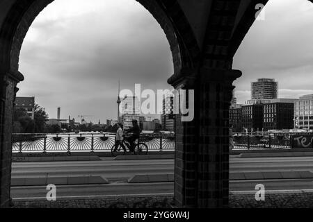 Vue en noir et blanc à travers les piliers du pont Oberbaum (Oberbaumbrücke) et Spree et fond de paysage urbain, Berlin, Allemagne, Europe Banque D'Images