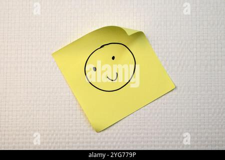 Attitude positive et concept heureux. Dessiné à la main Une émotion de visage de sourire sur fond de note collante. Banque D'Images