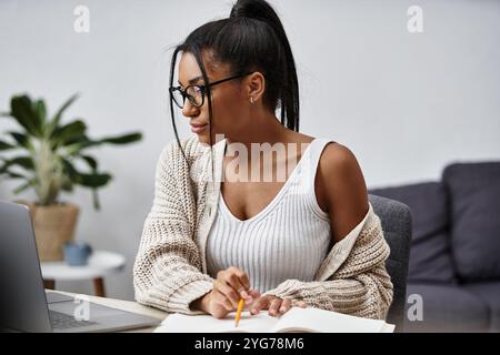 Une jeune femme s’engage dans ses études à la maison, immergée dans l’apprentissage avec concentration et grâce. Banque D'Images