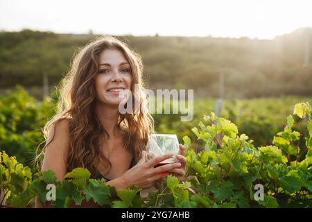 Belle femme avec un verre de fina dans le vignoble avant la récolte avec le sourire Banque D'Images