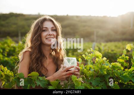 Belle femme avec un verre de fina dans le vignoble avant la récolte avec le sourire Banque D'Images