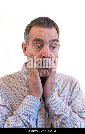 l'homme blanc d'âge moyen tient ses joues et regarde avec étonnement sa moustache à moitié manquante Banque D'Images