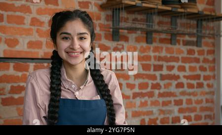 Portrait souriant femme indienne serveuse barista dans le tablier posant dans le café cafétéria avec les bras croisés confiants fille arabe femme petite entreprise café Banque D'Images