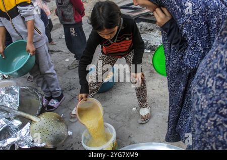 Gaza City, Palestine. 06 novembre 2024. Des Palestiniens déplacés de Beit Lahia et Jabalia reçoivent de la nourriture distribuée par des organisations caritatives dans le quartier de Nasser, dans la ville de Gaza, à Gaza. La crise alimentaire à Gaza se poursuit en raison du blocus israélien qui a été durci ces derniers jours. Crédit : SOPA images Limited/Alamy Live News Banque D'Images